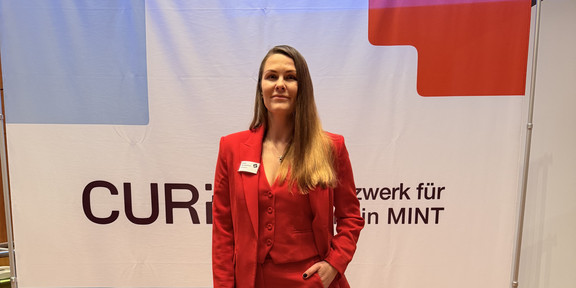 Natalia Ogorelysheva in front of a CURIA poster